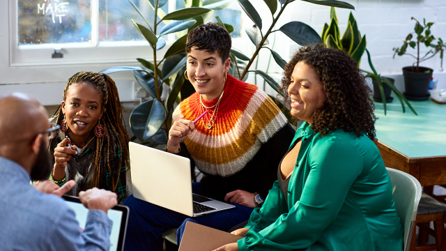 women gathered around a computer talking and working