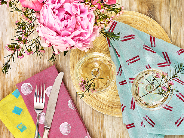 A table display of flowers and colourful printed napkins